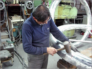 木槌でアルミを叩いて成形するタタキ板金の作業